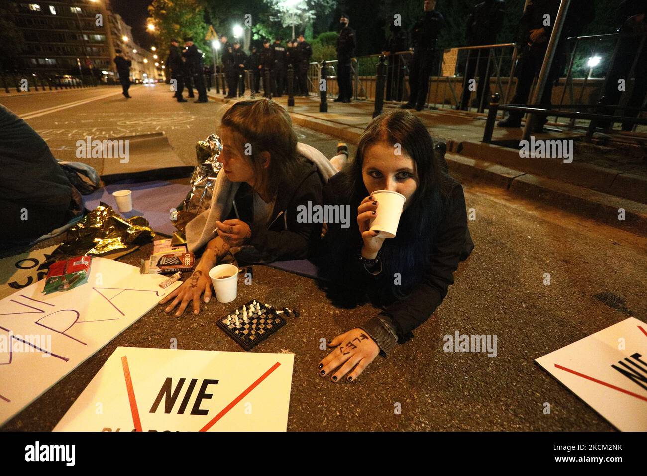 Zwei junge Frauen, die mit einer Hand auf die Straße geklebt sind, werden am 6. September 2021 bei einem Protest vor dem parlament in Warschau, Polen, gesehen. Mehrere hundert Demonstranten versammelten sich vor dem polnischen parlament Sejm, um gegen ein Präsidentendekret zu protestieren, das den Ausnahmezustand entlang der Grenzregion zu Belarus ausrief. Während Befürworter argumentieren, dass Polen von einem hybriden Krieg von Belarus bedroht sei, der Migranten aus dem Nahen Osten über die Grenze treibt, argumentieren Gegner, dass das Gesetz ein politisches Instrument sei, das zu weiterem Missbrauch gefährdeter Menschen führt. Polen wurde des illegalen Drückens beschuldigt Stockfoto