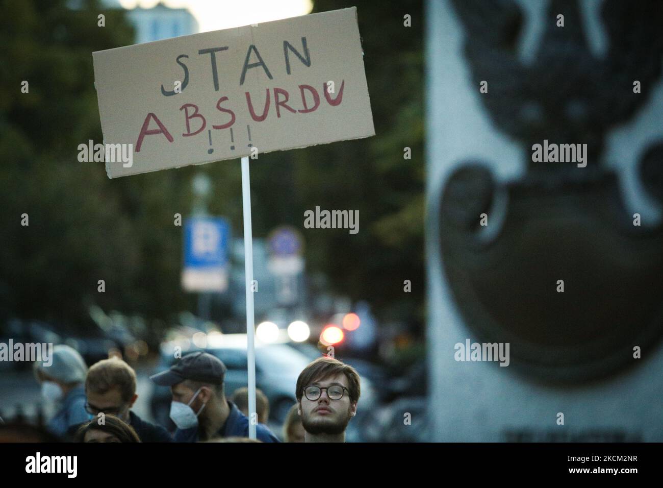 Am 6. September 2021 hält ein Mann ein Schild mit der Aufschrift „State of Absurdity“ vor dem parlament in Warschau, Polen. Mehrere hundert Demonstranten versammelten sich vor dem polnischen parlament Sejm, um gegen ein Präsidentendekret zu protestieren, das den Ausnahmezustand entlang der Grenzregion zu Belarus ausrief. Während Befürworter argumentieren, dass Polen von einem hybriden Krieg von Belarus bedroht sei, der Migranten aus dem Nahen Osten über die Grenze treibt, argumentieren Gegner, dass das Gesetz ein politisches Instrument sei, das zu weiterem Missbrauch gefährdeter Menschen führt. Polen wurde beschuldigt, Migranten illegal zurückgeschickt zu haben Stockfoto