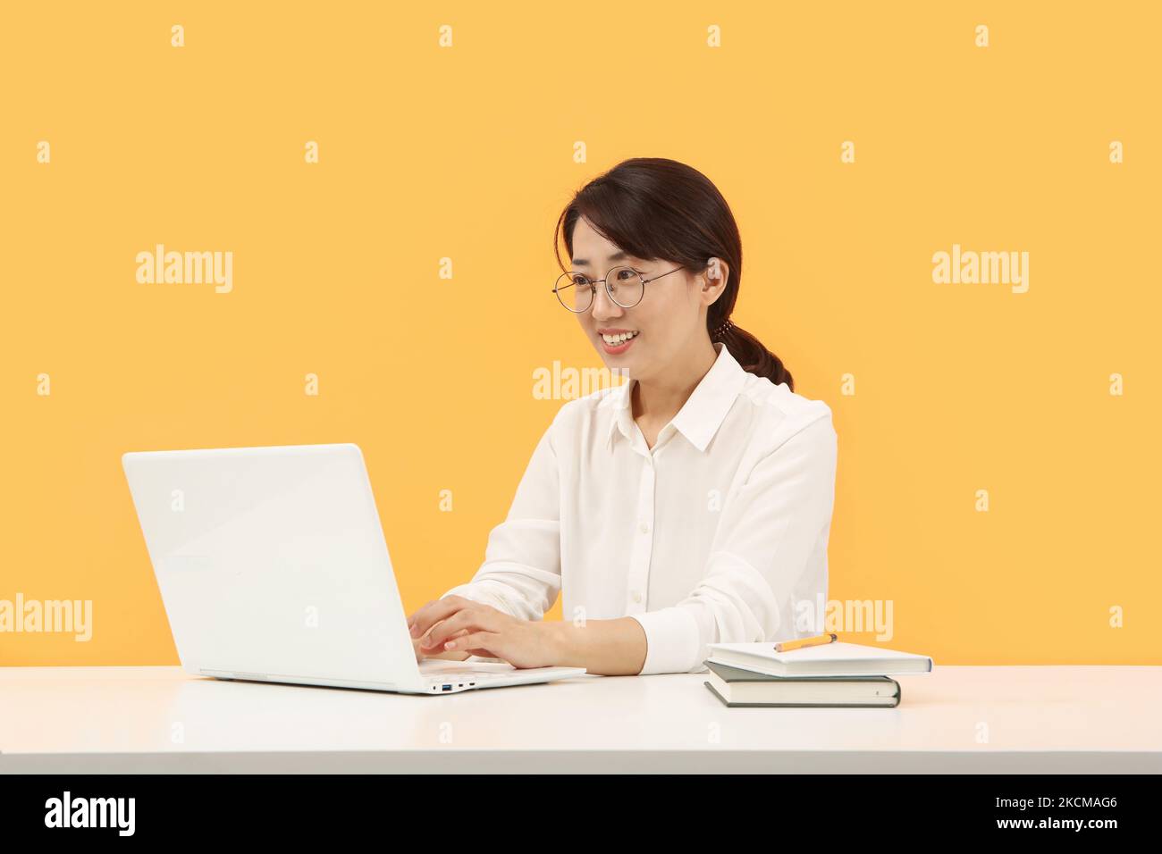 Moderne Büroangestellte Frau, die zu Hause oder im Büro freundlich lächelt und von zu Hause aus über das Internet online auf dem Laptop arbeitet Stockfoto