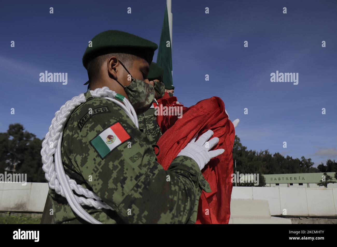 Mitglieder des Sekretariats der Nationalen Verteidigung (SEDENA) senken die mexikanische Flagge auf der Esplanade der Bekleidungs- und Ausrüstungsfabrik El Vergel Iztapalapa, Mexiko-Stadt, während des Gesundheitsnotfalls COVID-19 und der gelben epidemiologischen Ampel in der Hauptstadt. (Foto von Gerardo Vieyra/NurPhoto) Stockfoto