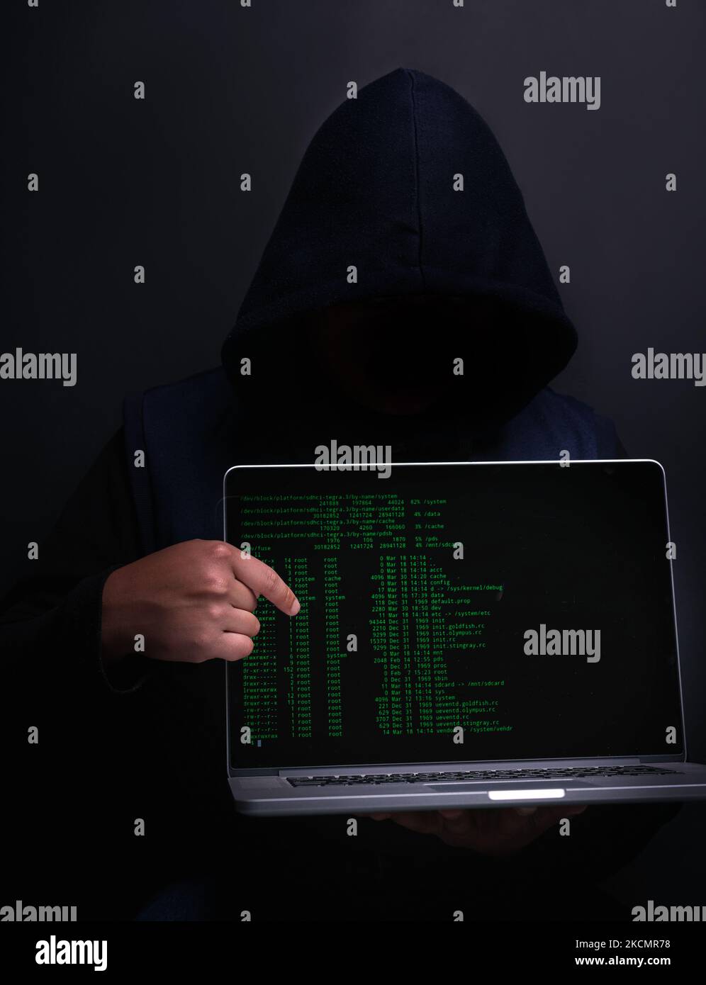Du könntest das nächste Opfer sein. Porträt eines nicht erkennbaren Hackers, der einen Laptop vor einem dunklen Hintergrund hochhält. Stockfoto
