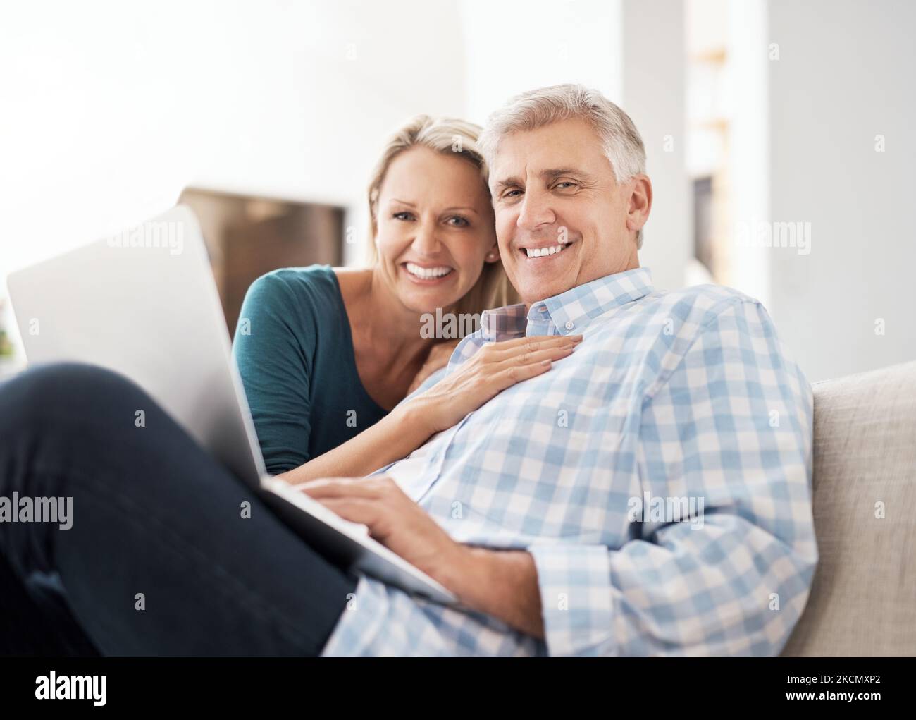 Alles, was ich brauche, ist hier auf diesem Sofa. Porträt eines liebevollen, reifen Paares, das einen Laptop benutzt, während es zu Hause auf dem Sofa sitzt. Stockfoto