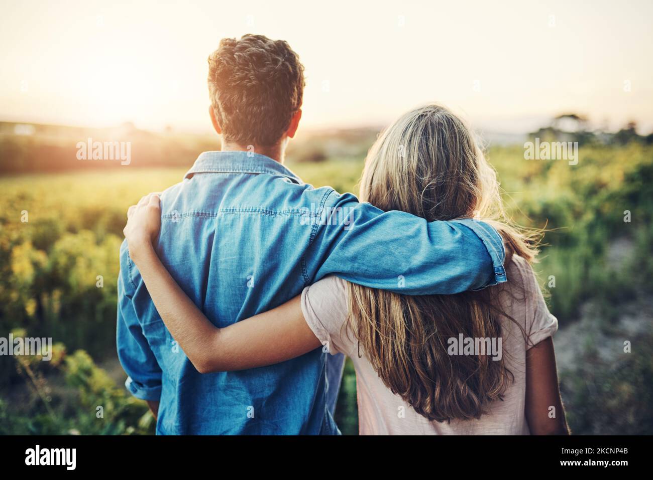 Unsere Farm ist eine Arbeit der Liebe, für die wir leben. Rückansicht eines liebevollen jungen Paares, das auf dem Bauernhof über ihre Ernte schaut. Stockfoto