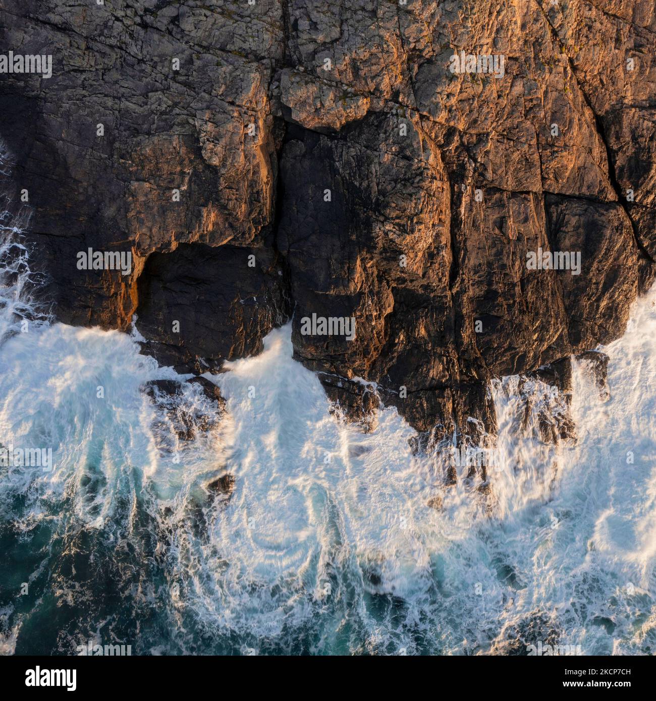 Wunderschöne Luftdrohnen-Landschaftsaufnahme aus der Vogelperspektive von Wellen, die über Felsen an der Küste krachen Stockfoto