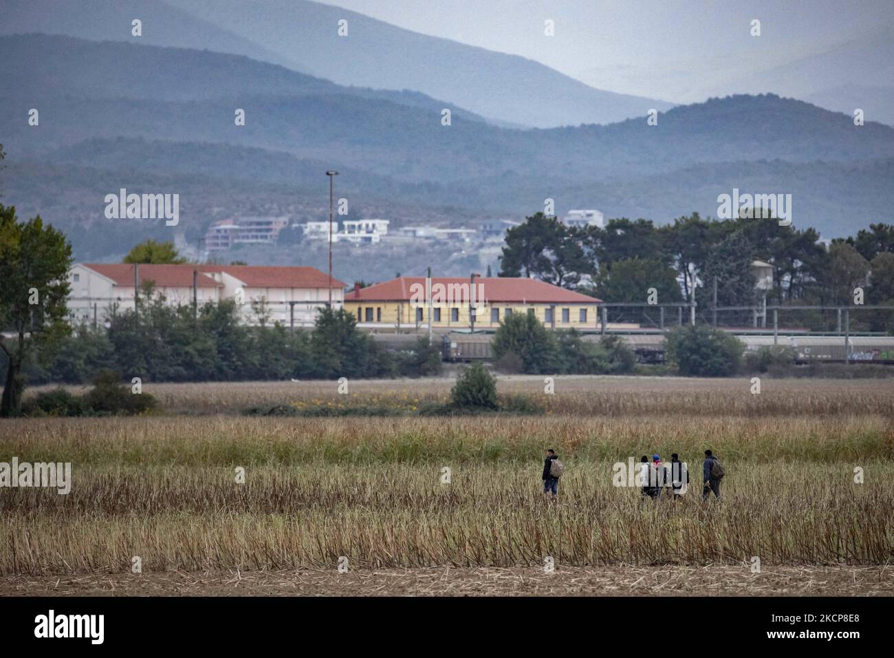 Migranten werden auf den Feldern mit dem ikonischen gelben Bahnhof von Idomeni und den Häusern in Nordmakedonien im Hintergrund gesehen. Asylbewerber versuchen, die griechisch-nordmazedonischen Grenzen zu überqueren, um der 2015-2016 während der syrischen Flüchtlingskrise berühmten Balkanroute zu folgen, von Idomeni, Griechenland, nach Gevgelija, Nord-Mazedonien, den Bahnschienen und dem Bahnhof folgend, um dann Mittel- und Nordeuropa zu erreichen. Flüchtlinge und Migranten werden auf den Feldern auf der griechischen Seite gesehen, vor dem Zaun, der die beiden Länder trennt, und versuchen, die Grenzen zu erreichen und zu passieren. Der kleine gr Stockfoto