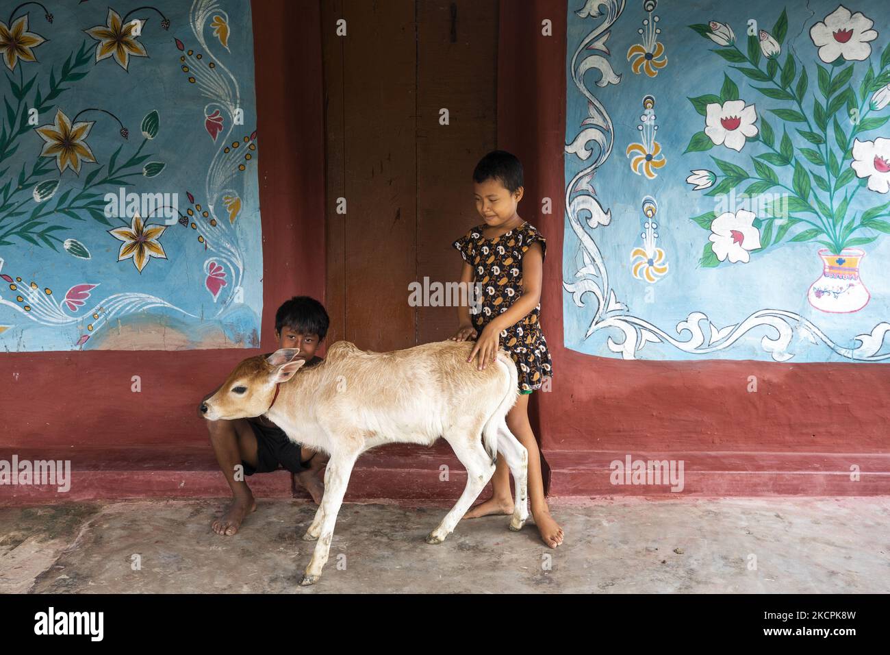 Kinder spielen am 8. Oktober 2021 im Dorf Alpona in chapainawabganj mit einem Jungen. Die Einheimischen sagen, dass die Alpanaculture aus den abgelegenen Dörfern des größeren Rajshahi der Hindu-Familie stammt. Die meisten Häuser hier sind aus Lehm. Vor verschiedenen Tithin-Festen gab es drei Tropfen auf die Lehmwände dieses Hauses, und die weißen Snacks wurden abgerissen. Jetzt sind drei Töne nicht gezeichnet, bemalte Blumen, Vögel, Himmel, Flüsse und die klassischen Bilder von Bengalen. (Foto von Ahmed Salahuddin/NurPhoto) Stockfoto