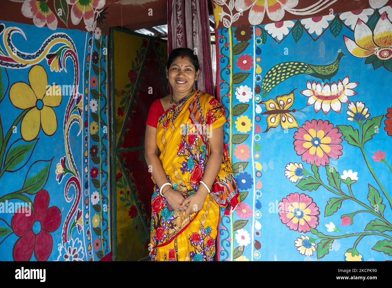 Eine Resident-Pose für ein Porträt im Dorf Alpona in chapainawabganj am 8. Oktober 2021. Die Einheimischen sagen, dass die Alpanaculture aus den abgelegenen Dörfern des größeren Rajshahi der Hindu-Familie stammt. Die meisten Häuser hier sind aus Lehm. Vor verschiedenen Tithin-Festen gab es drei Tropfen auf die Lehmwände dieses Hauses, und die weißen Snacks wurden abgerissen. Jetzt sind drei Töne nicht gezeichnet, bemalte Blumen, Vögel, Himmel, Flüsse und die klassischen Bilder von Bengalen. (Foto von Ahmed Salahuddin/NurPhoto) Stockfoto