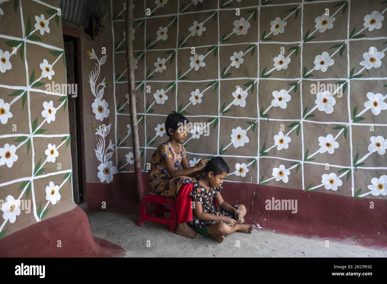 Am 8. Oktober 2021 helfen sich die Kinder gegenseitig, Läuse im Dorf Alpona in chapainawabganj loszuwerden. Die Einheimischen sagen, dass die Alpanaculture aus den abgelegenen Dörfern des größeren Rajshahi der Hindu-Familie stammt. Die meisten Häuser hier sind aus Lehm. Vor verschiedenen Tithin-Festen gab es drei Tropfen auf die Lehmwände dieses Hauses, und die weißen Snacks wurden abgerissen. Jetzt sind drei Töne nicht gezeichnet, bemalte Blumen, Vögel, Himmel, Flüsse und die klassischen Bilder von Bengalen. (Foto von Ahmed Salahuddin/NurPhoto) Stockfoto