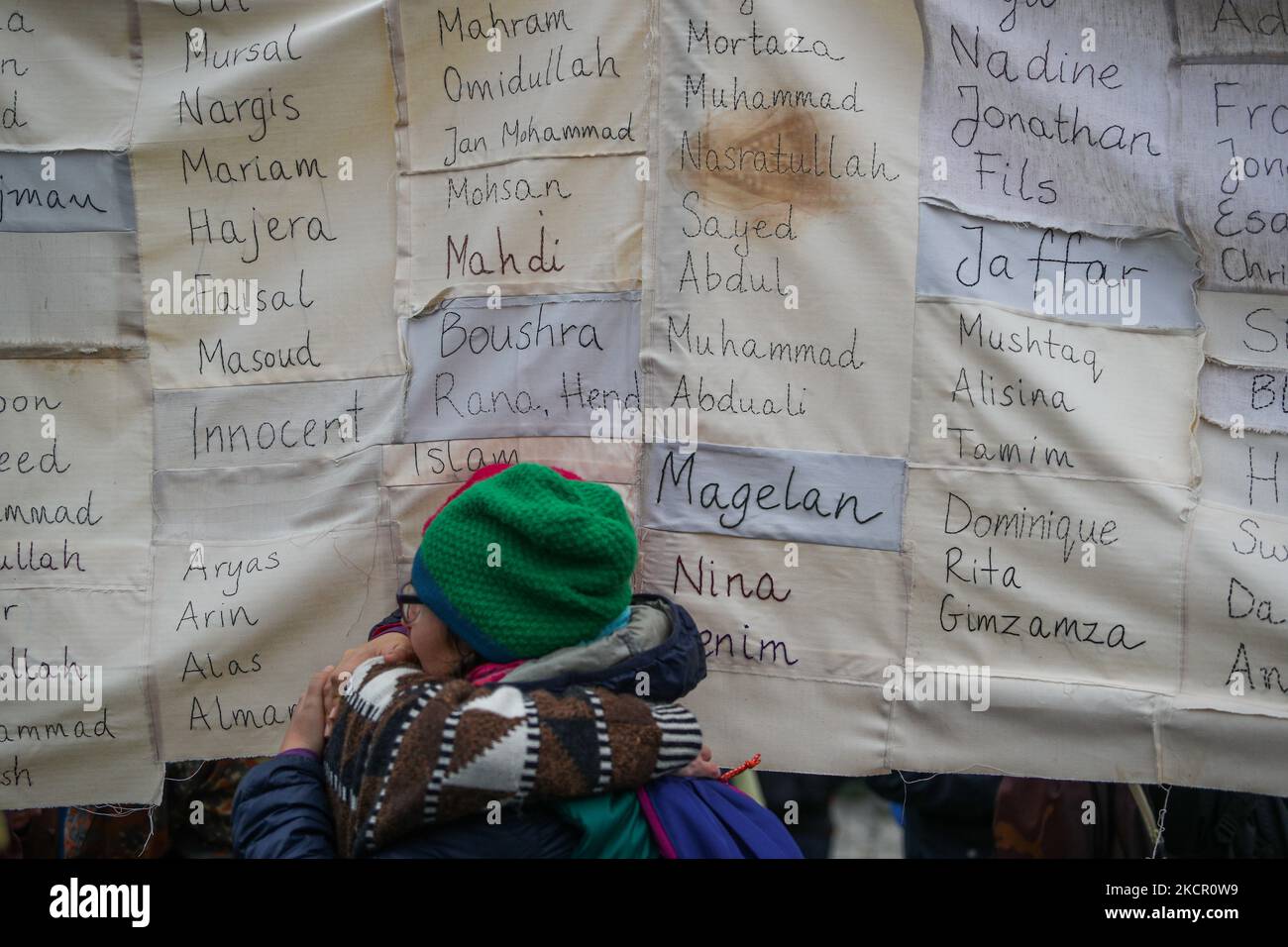 Bei einer Kundgebung, bei der sich am 17. Oktober mehr als tausend Menschen im Zentrum von Warschau, Polen, versammeln, werden zwei Frauen vor einem Schild mit den Namen der Flüchtlinge beobachtet, die die Grenze von Belarus nach Polen überschreiten. 2021 ein Ende illegaler Rückschläge an der Grenze zu Belarus zu fordern. Seit mehr als zwei Monaten schieben die polnischen Grenzschutzbeamten Tausende von Migranten zurück, die von Belarus aus in einem vom Lukaschenko-Regime orchestrierten hybriden Krieg über die Grenze gezwungen wurden. Der Druck auf die polnische Regierung wird erhöht, nachdem mehr als ein halbes Dutzend Migranten im Grenzgebiet gestorben sind Stockfoto