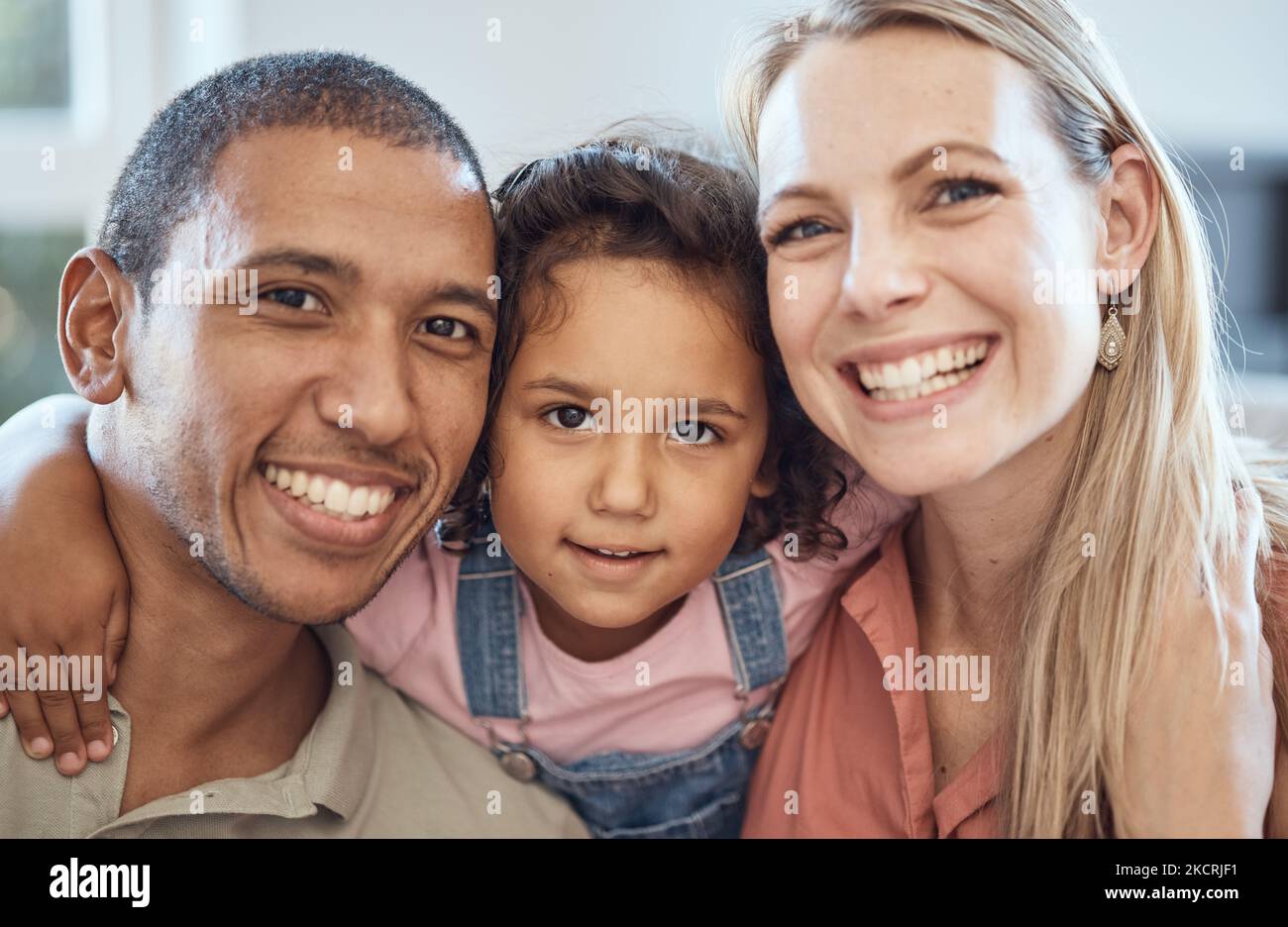 Fröhliche, lächelnde und interracial Eltern mit ihrem Kind sitzen, miteinander verbinden und entspannen. Porträt einer Mutter, eines Vaters und eines Kindes mit Glück Stockfoto
