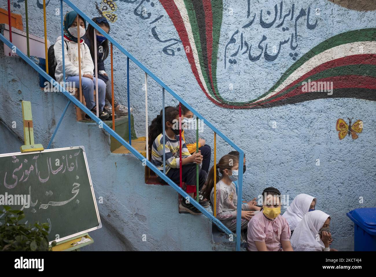 Afghanische Flüchtlingsschüler sitzen am ersten Tag des neuen Studienjahres auf der Treppe der Farhang-Schule? Am 1. November 2021 in Südtehran. Die Farhang-Schule wurde 2000 vom afghanischen Flüchtling Nader Mousavi gegründet, der einen Master-Abschluss in Soziologie an der Universität von Teheran gemacht hat. Und jetzt, zwei Jahre nach dem Beginn des COVID-19-Ausbruchs im Iran, wo die Schule in Teilzeit betrieben wurde, hat sie ihren Vollzeitbetrieb aufgenommen und afghanische Schülerinnen und Schüler können die Schule besuchen. Familien müssen kein Geld für den Unterricht bezahlen, da er für Einen Kostenlos ist Stockfoto