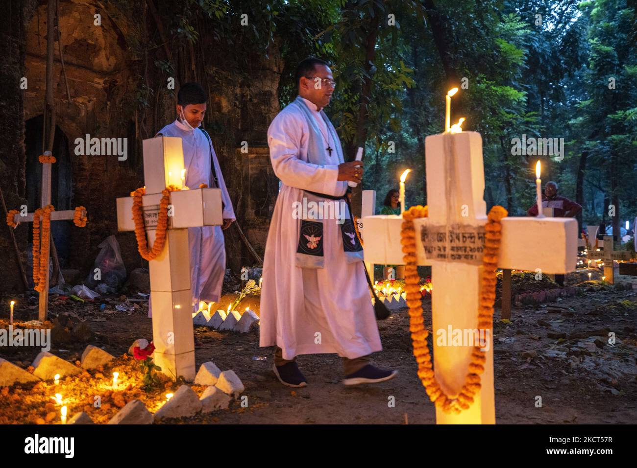 Ein Priester, der als Familie Gebete rezitiert, betet für seinen verstorbenen Verwandten, um den All Souls Day am 2. November 2021 auf einem Friedhof in Dhaka zu feiern. (Foto von Ahmed Salahuddin/NurPhoto) Stockfoto