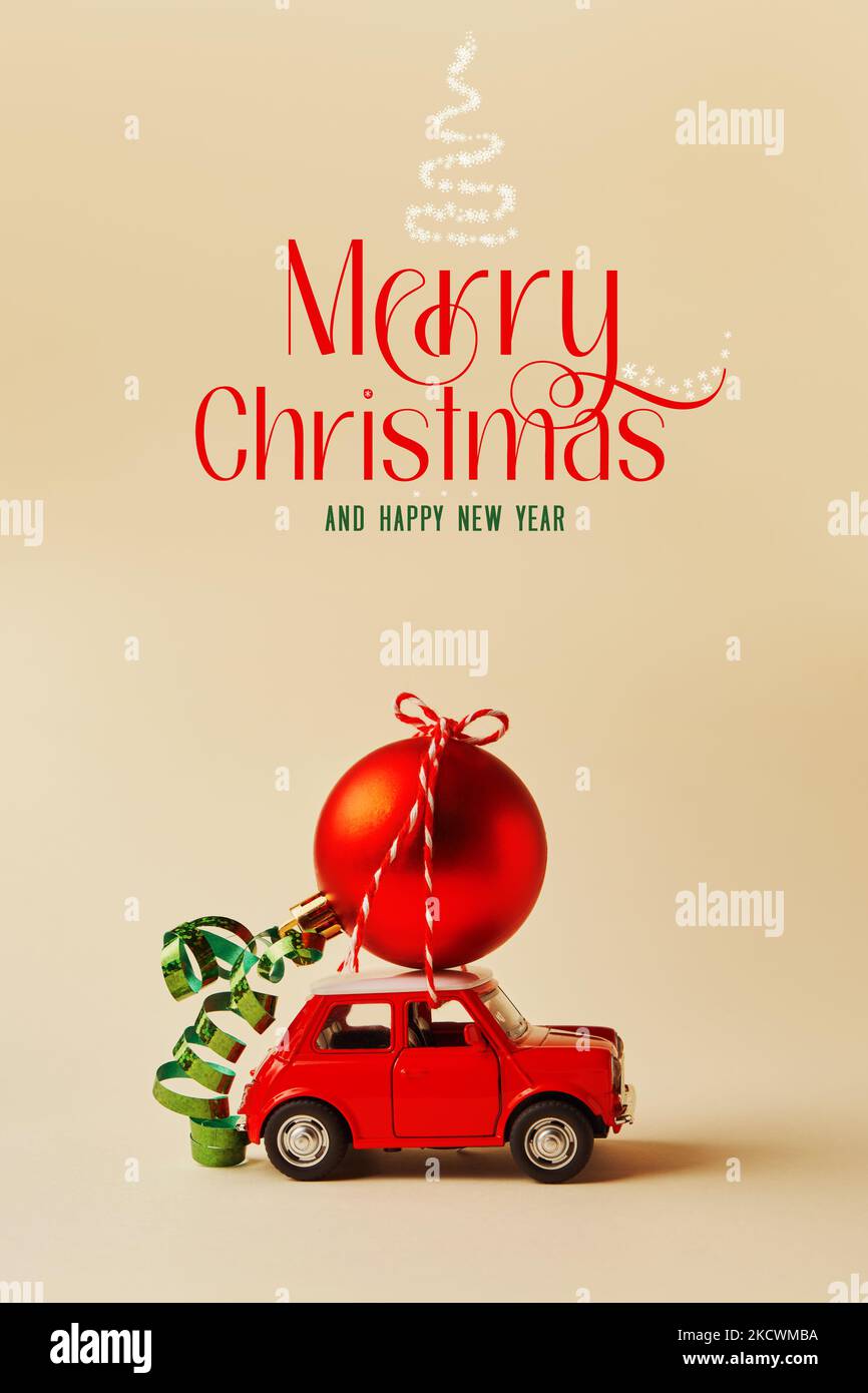Rotes Retro-Spielzeugauto mit einem roten Weihnachtsball auf Vintage-Hintergrund mit Text Stockfoto