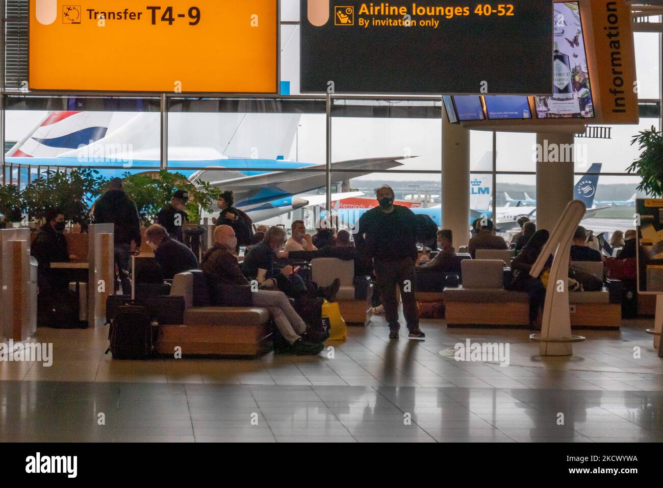 Passagiere, die vor dem Flugzeug sitzen. Im Terminal des internationalen Flughafens Amsterdam Schiphol AMS während der Pandemie Covid-19. 14 Fälle der neuen COVID-19-Variante Omicron wurden in den Niederlanden von Passagieren bestätigt, die aus Südafrika in die niederländische Stadt kamen. Mehr als 600 Passagiere wurden von den 2 Flügen getestet, wobei 61 positiv für Covid-19 bestätigt wurden. Die niederländische Polizei verhaftete zuvor zwei Passagiere, die sich in einem Quarantänehotel aufgehalten haben, als sie versuchten zu entkommen. Viele Länder haben Flüge nach Südafrika während einer bereits schwierigen Zeit mit dem Coronavirus eingestellt Stockfoto