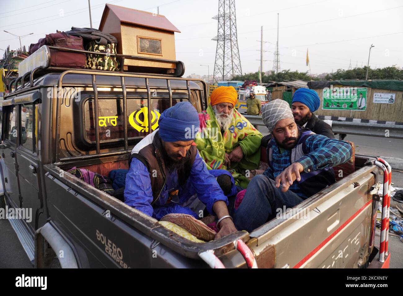 Die Bauern steigen auf einem Lastwagen ein, während sie eine Proteststelle räumen, nachdem die Regierung am 12. Dezember 2021 in Ghazipur, am Stadtrand von Neu-Delhi, Indien, zugestimmt hatte, eine Reihe von Fragen zu akzeptieren, darunter die Versicherung des Mindeststützungspreises (MSP). (Foto von Mayank Makhija/NurPhoto) Stockfoto