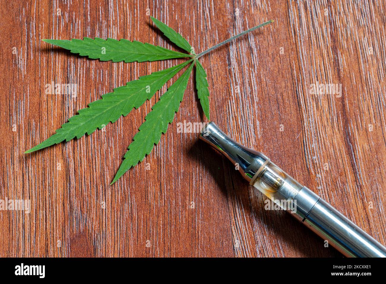 CBD-Verdampfer mit einem Hintergrund aus Cannabisblättern Stockfoto