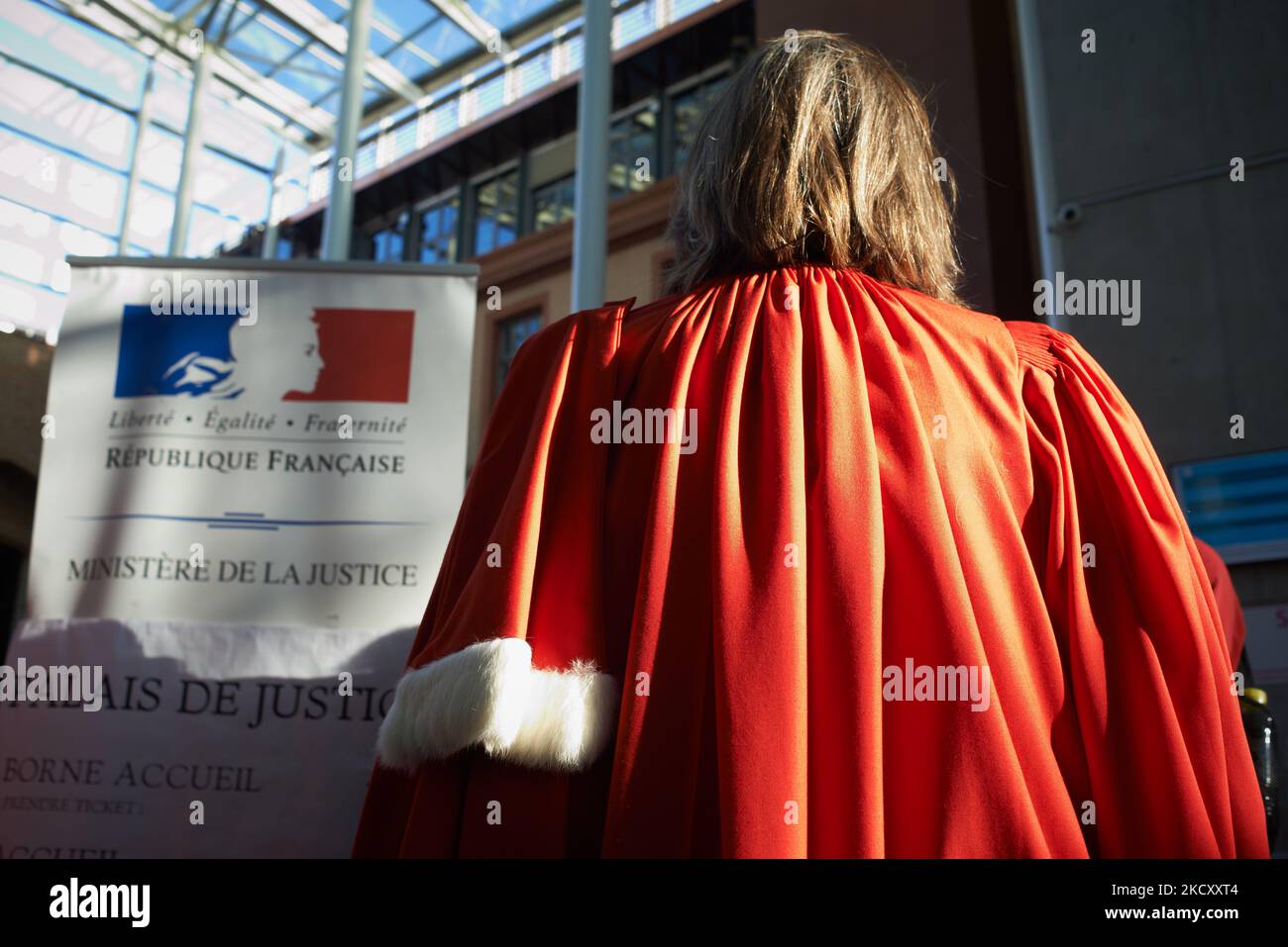 Ein Richter steht neben einem Schild mit der Aufschrift „Französische Republik, Justizministerium“. Alle Gewerkschaften der Justiz, von Gerichtsbeamten bis hin zu Richtern und Anwälten (SAF, USM, SM, Syndicat des Greffiers usw.), riefen zu einem Streik und einer Versammlung im Gerichtsgebäude von Toulouse wie anderswo in Frankreich auf, um hauptsächlich gegen den Mangel an Mitteln zu protestieren, um gute Arbeit zu leisten. Richter, Anwälte und Beamte klagen über einen Sinnverlust für ihre Arbeit, als sie fragen: „Wie gut könnte man Gerechtigkeit üben, wenn man mehr als 10 Stunden urteilt?“ Die Richter erkennen an, dass die Justiz zu langsam ist, aber gerade in Toulouse das Justizsystem Stockfoto