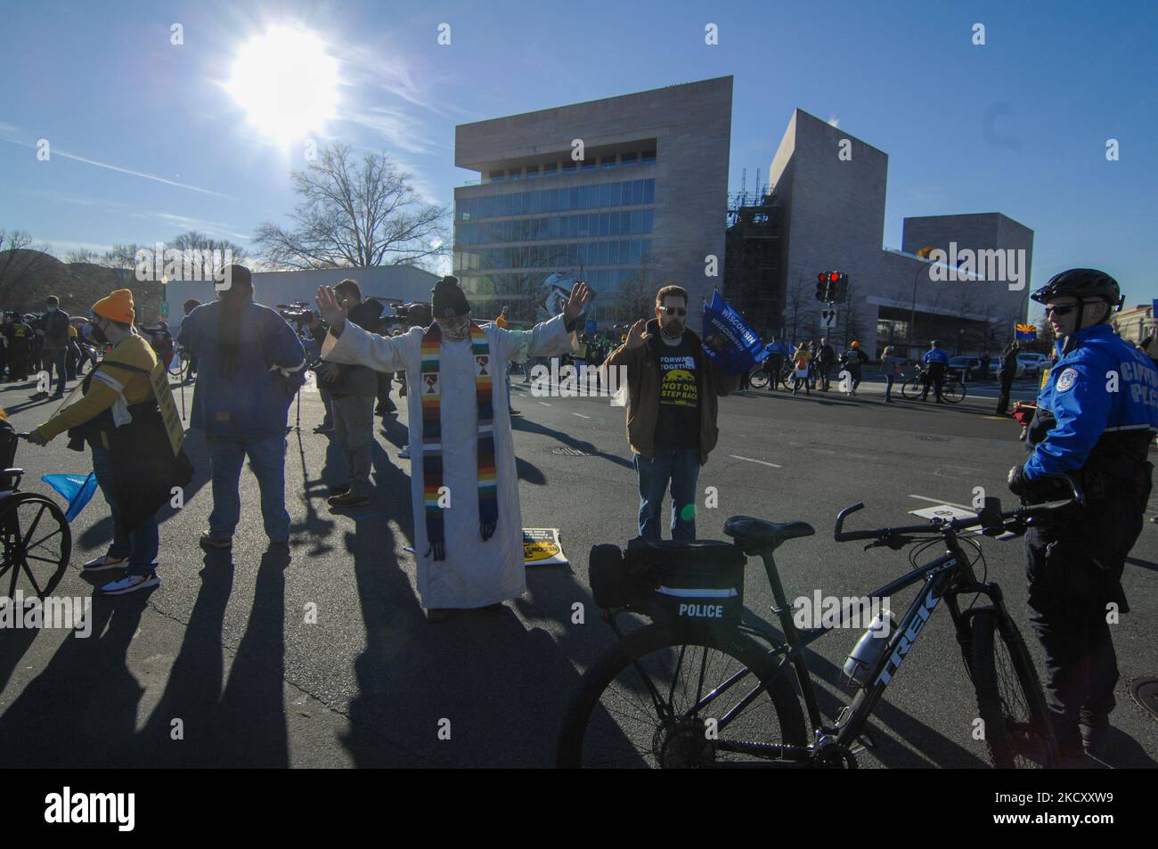 Ein Mitglied des Klerus betet für die Polizeibeamten des Kapitols, die sie verhaften werden, weil sie friedlich auf der Straße stehen, um zu fordern, dass der Kongress den Build Back Better Act während einer Kundgebung verabschiedet und am 13. Dezember 2021 vor dem US-Kapitol in Washington D.C. marschieren wird. (Foto von Cory Clark/NurPhoto) Stockfoto
