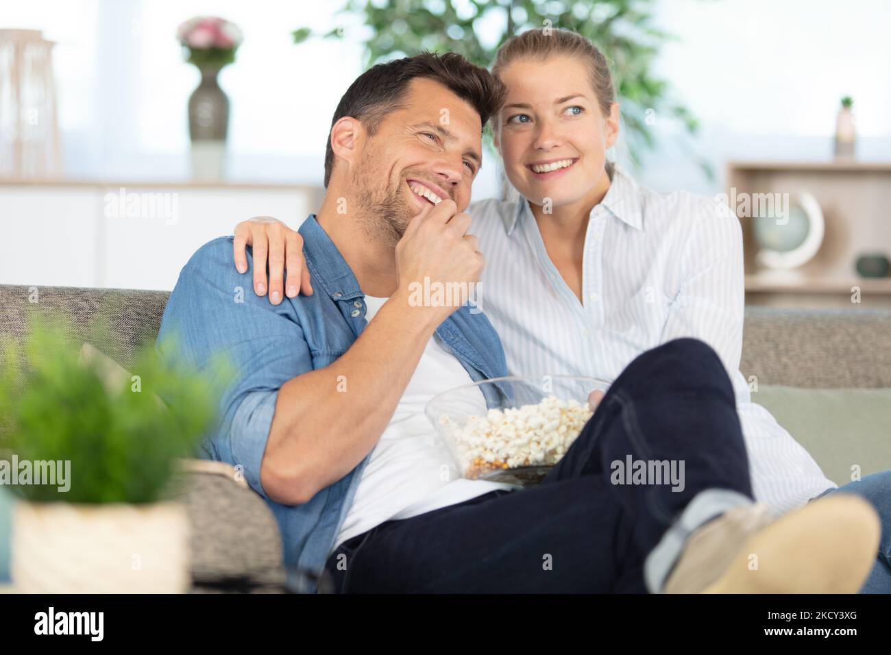 Glückliches Paar auf dem Sofa mit Popcorn beim Fernsehen Stockfoto