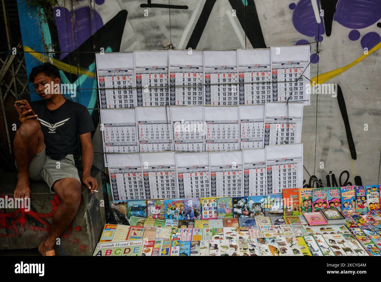 Ein Straßenverkäufer verkauft 2022 Kalender warten auf einen Kunden in einer Straße in Bogor, Indonesien, am 28. Dezember 2021. (Foto von Adriana Adie/NurPhoto) Stockfoto