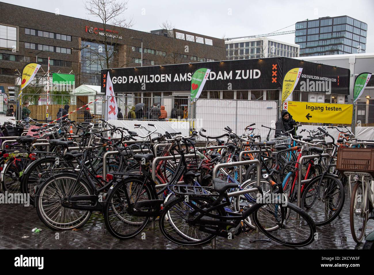 Geparkte Fahrräder vor der Testanlage des GGD Paviljoen Amsterdam. Menschen warten in der Schlange, um vor einem GGD Covid-19 Testzentrum getestet zu werden, GGD ist der städtische Gesundheitsdienst in Amsterdam Zuid. Die Niederlande waren die erste europäische Nation, die kurz vor Weihnachten während der Coronavirus-Pandemie von Covid-19 eine Sperre gegen die neue Omicron-Variante ausrief. Bars, Fitnessstudios, Friseure und alle „nicht notwendigen“ Geschäfte, Museen, öffentlichen Einrichtungen usw. waren bis mindestens Januar 14 geschlossen. Amsterdam, Niederlande am 5. Januar 2022 (Foto von Nicolas Economou/NurPhoto) Stockfoto