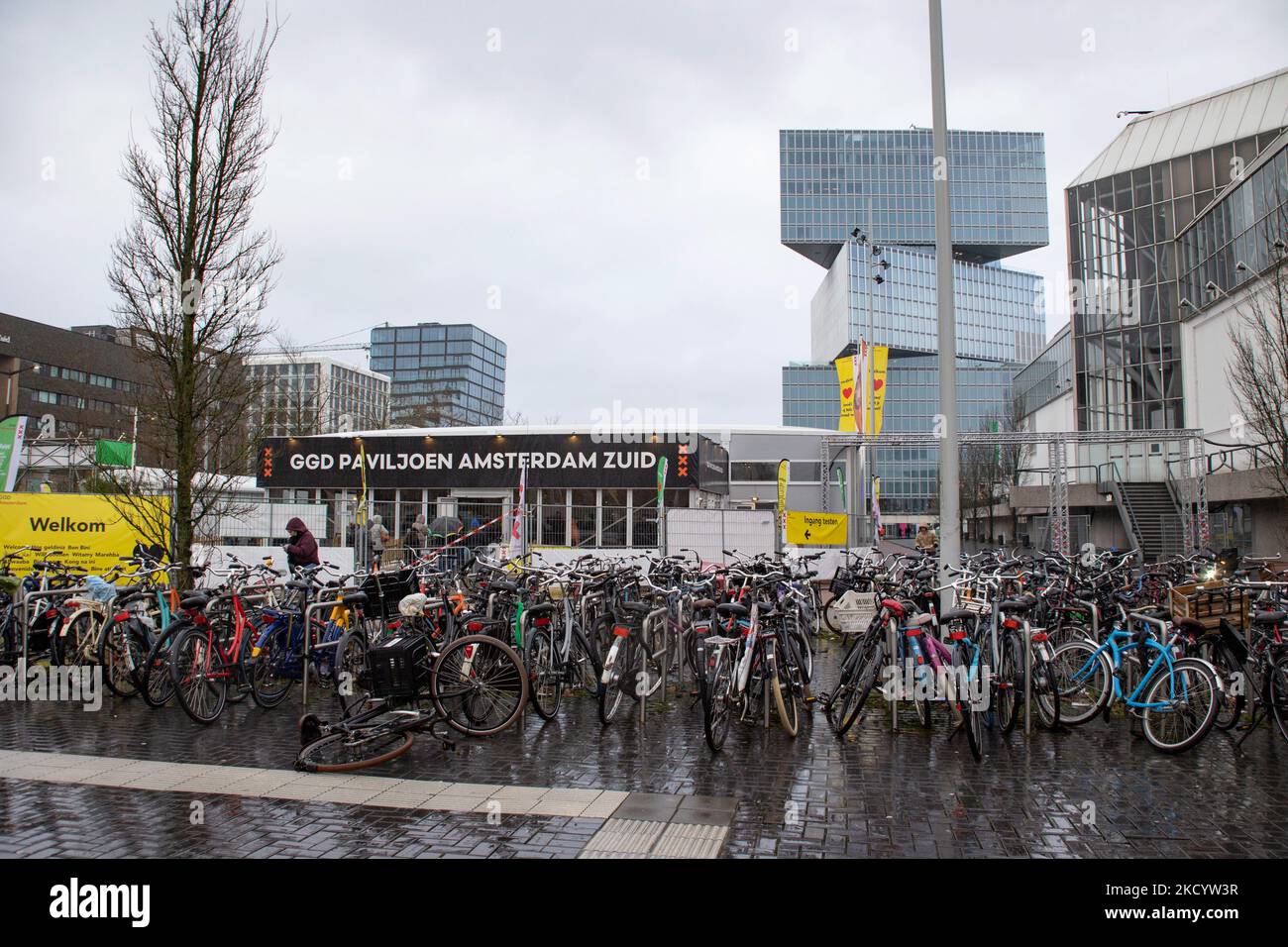 Geparkte Fahrräder vor der Testanlage des GGD Paviljoen Amsterdam. Menschen warten in der Schlange, um vor einem GGD Covid-19 Testzentrum getestet zu werden, GGD ist der städtische Gesundheitsdienst in Amsterdam Zuid. Die Niederlande waren die erste europäische Nation, die kurz vor Weihnachten während der Coronavirus-Pandemie von Covid-19 eine Sperre gegen die neue Omicron-Variante ausrief. Bars, Fitnessstudios, Friseure und alle „nicht notwendigen“ Geschäfte, Museen, öffentlichen Einrichtungen usw. waren bis mindestens Januar 14 geschlossen. Amsterdam, Niederlande am 5. Januar 2022 (Foto von Nicolas Economou/NurPhoto) Stockfoto