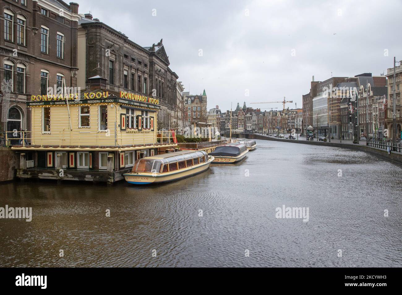 Die leeren Kanäle von Amsterdam mit den Touristenbooten dockten an. Ruhige, fast menschenleere Straßen von Amsterdam während der Sperre in der niederländischen Hauptstadt mit Geschäften und Geschäften, die mit geschlossenen Rollläden aus Metall erscheinen, Cafés, Bars und Restaurants, die auch mit geschlossenen Tischen und Stühlen der Terrassen geschlossen sind. Die Niederlande waren die erste europäische Nation, die die vollständige Sperre erklärte, um gegen die neue Omicron-Variante zu kämpfen, die aufkommt. Nach einem plötzlichen Regierungsbefehl vor Weihnachten schloss das Land alle unwesentlichen Geschäfte, Cafés, Restaurants, Bars, Stockfoto