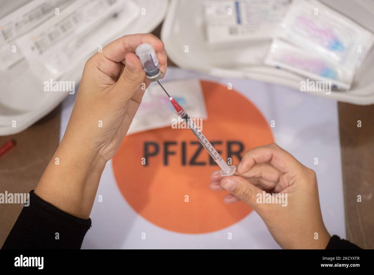 Nahaufnahme des Fläschchens mit der Aufschrift Comirnaty, mRNA usw., der Nadel und der Spritze, während eine GGD-Mitarbeiterin die Pfizer - BioNTech Covid-19-Impfstoffe vorbereitet, die sie aus der Fläschchenglasflasche zu den Spritzen im Sonderbereich des Mega-Impfzentrums in Eindhoven zieht. Die Jabs werden als Booster-Schuss verabreicht. Der dritte Dosisverstärker ist für alle in den Niederlanden verfügbar, zusätzlich zur Sperrung, da das Land gegen Ausbrüche der neuen omicron-Variante-Coronavirus-Mutation der Pandemie kämpft. Eindhoven, Niederlande am 7. Januar 2022 (Foto: Nicolas Economou/N Stockfoto