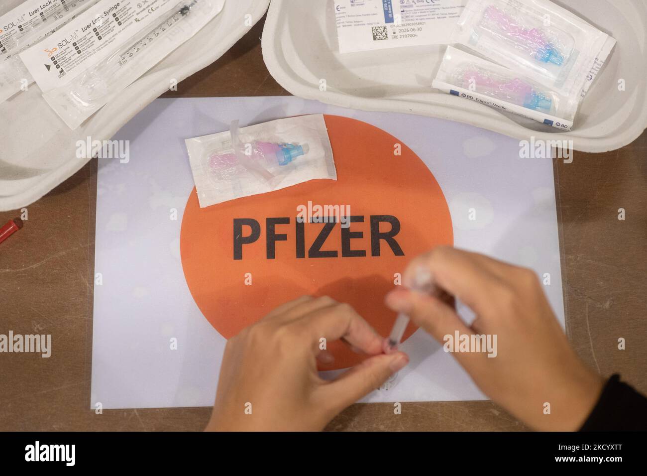 Nahaufnahme des Fläschchens mit der Aufschrift Comirnaty, mRNA usw., der Nadel und der Spritze, während eine GGD-Mitarbeiterin die Pfizer - BioNTech Covid-19-Impfstoffe vorbereitet, die sie aus der Fläschchenglasflasche zu den Spritzen im Sonderbereich des Mega-Impfzentrums in Eindhoven zieht. Die Jabs werden als Booster-Schuss verabreicht. Der dritte Dosisverstärker ist für alle in den Niederlanden verfügbar, zusätzlich zur Sperrung, da das Land gegen Ausbrüche der neuen omicron-Variante-Coronavirus-Mutation der Pandemie kämpft. Eindhoven, Niederlande am 7. Januar 2022 (Foto: Nicolas Economou/N Stockfoto