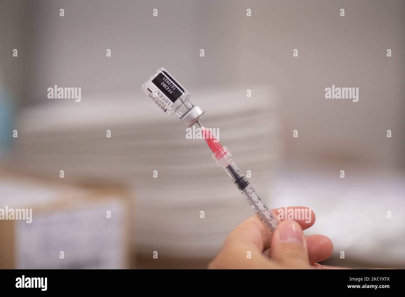 Nahaufnahme des Fläschchens mit der Aufschrift Comirnaty, mRNA usw., der Nadel und der Spritze, während eine GGD-Mitarbeiterin die Pfizer - BioNTech Covid-19-Impfstoffe vorbereitet, die sie aus der Fläschchenglasflasche zu den Spritzen im Sonderbereich des Mega-Impfzentrums in Eindhoven zieht. Die Jabs werden als Booster-Schuss verabreicht. Der dritte Dosisverstärker ist für alle in den Niederlanden verfügbar, zusätzlich zur Sperrung, da das Land gegen Ausbrüche der neuen omicron-Variante-Coronavirus-Mutation der Pandemie kämpft. Eindhoven, Niederlande am 7. Januar 2022 (Foto: Nicolas Economou/N Stockfoto