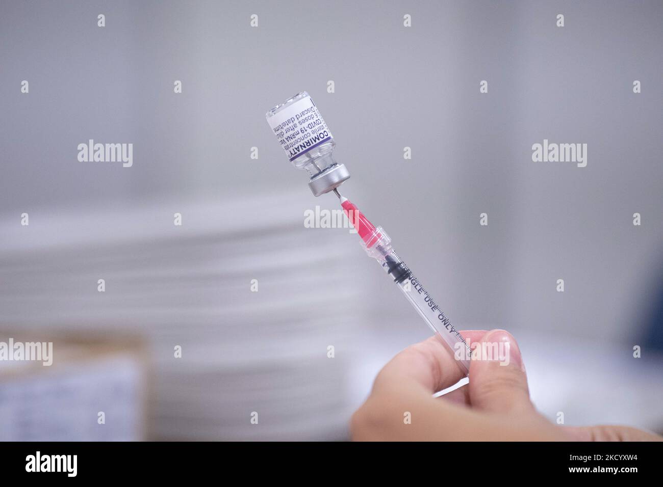 Nahaufnahme des Fläschchens mit der Aufschrift Comirnaty, mRNA usw., der Nadel und der Spritze, während eine GGD-Mitarbeiterin die Pfizer - BioNTech Covid-19-Impfstoffe vorbereitet, die sie aus der Fläschchenglasflasche zu den Spritzen im Sonderbereich des Mega-Impfzentrums in Eindhoven zieht. Die Jabs werden als Booster-Schuss verabreicht. Der dritte Dosisverstärker ist für alle in den Niederlanden verfügbar, zusätzlich zur Sperrung, da das Land gegen Ausbrüche der neuen omicron-Variante-Coronavirus-Mutation der Pandemie kämpft. Eindhoven, Niederlande am 7. Januar 2022 (Foto: Nicolas Economou/N Stockfoto