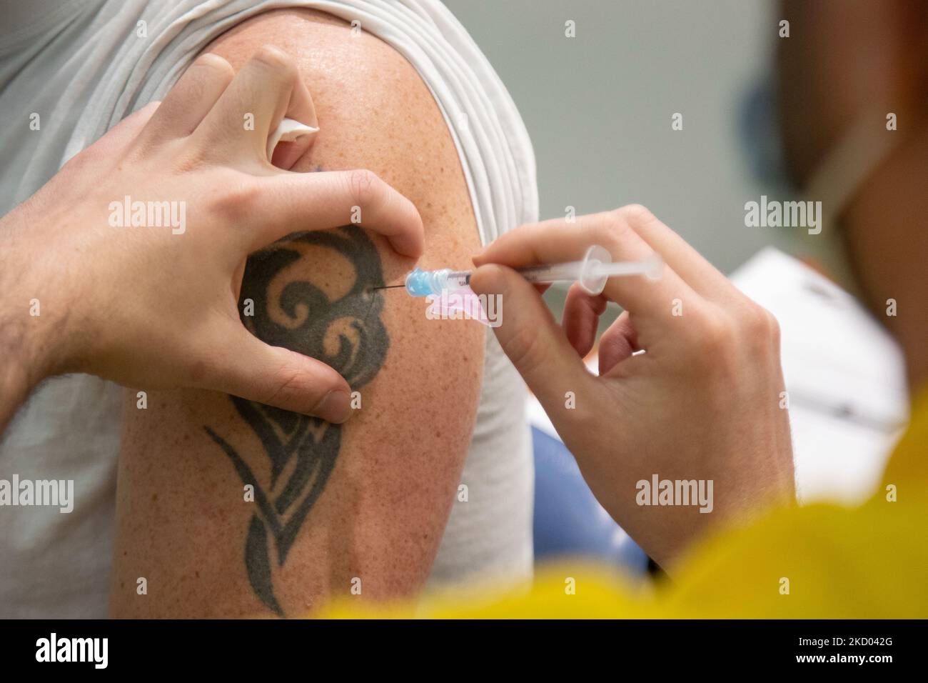 Nahaufnahme am Arm mit einem Tatoo während der Impfung eines Mannes. Impfzentrum in Eindhoven mit 20 Bahnen und einer Kapazität von 7500 Impfstoffen pro Tag. Die Jabs werden von GGD-Mitarbeitern im Gesundheitswesen als Auffrischungsimpfung verabreicht, um vor Covid-19 zu schützen. Der dritte Dosis-Booster ist für alle in den Niederlanden erhältlich. Das Land befindet sich in einer Blockierung, da die Nation gegen den Ausbruch der neuen Omicron-Variante, sars-Cov-2-Coronavirus-Mutation der Pandemie, kämpft. Eindhoven, Niederlande am 7. Januar 2022 (Foto: Nicolas Economou/NurPhoto) Stockfoto