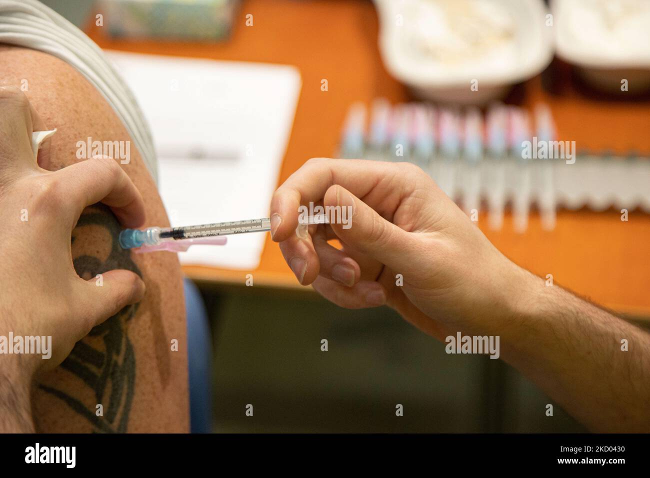 Nahaufnahme am Arm mit einem Tatoo während der Impfung eines Mannes. Impfzentrum in Eindhoven mit 20 Bahnen und einer Kapazität von 7500 Impfstoffen pro Tag. Die Jabs werden von GGD-Mitarbeitern im Gesundheitswesen als Auffrischungsimpfung verabreicht, um vor Covid-19 zu schützen. Der dritte Dosis-Booster ist für alle in den Niederlanden erhältlich. Das Land befindet sich in einer Blockierung, da die Nation gegen den Ausbruch der neuen Omicron-Variante, sars-Cov-2-Coronavirus-Mutation der Pandemie, kämpft. Eindhoven, Niederlande am 7. Januar 2022 (Foto: Nicolas Economou/NurPhoto) Stockfoto