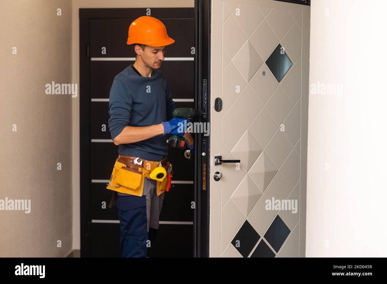 Bohren und Einbau von Innentüren, macht der Handwerker ein Loch in den Türrahmen mit einem Handbohrer, Türen und Montage Stockfoto