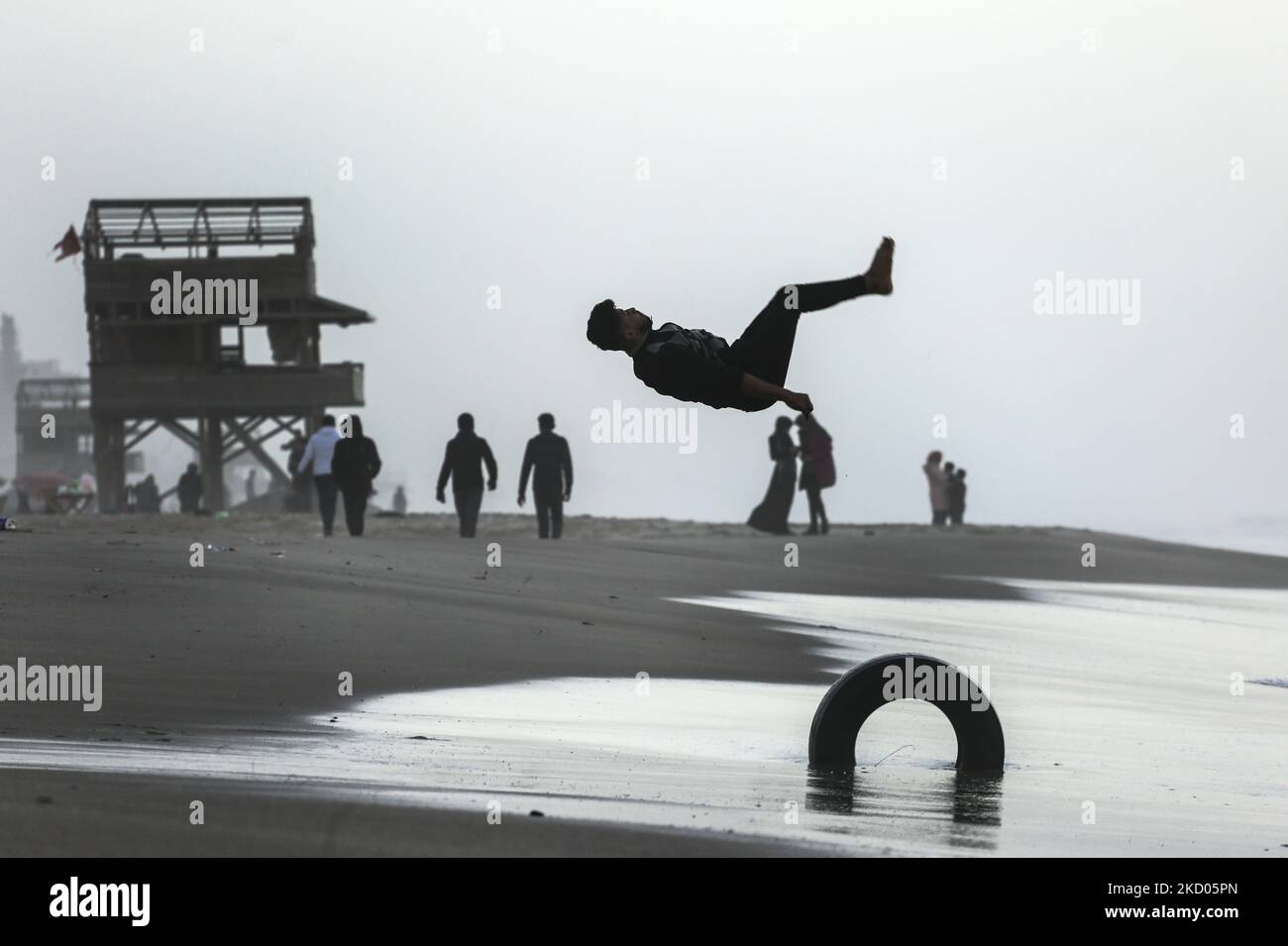 Ein palästinensischer Jugendlicher übt seine Parkour-Fähigkeiten am Strand von Gaza City während des Sonnenuntergangs am Montag, dem 10. Januar 2022. (Foto von Sameh Rahmi/NurPhoto) Stockfoto