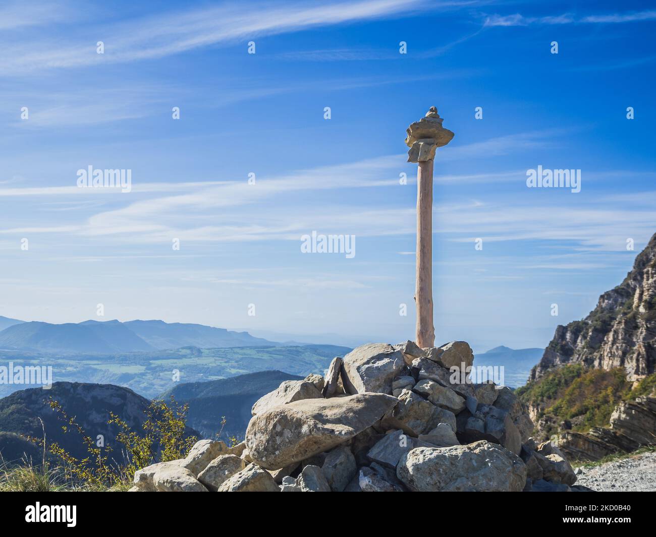 Steinturm mit einem Baumzweig auf einem Berg in den alpen mit Blick auf die umliegenden Berge Stockfoto