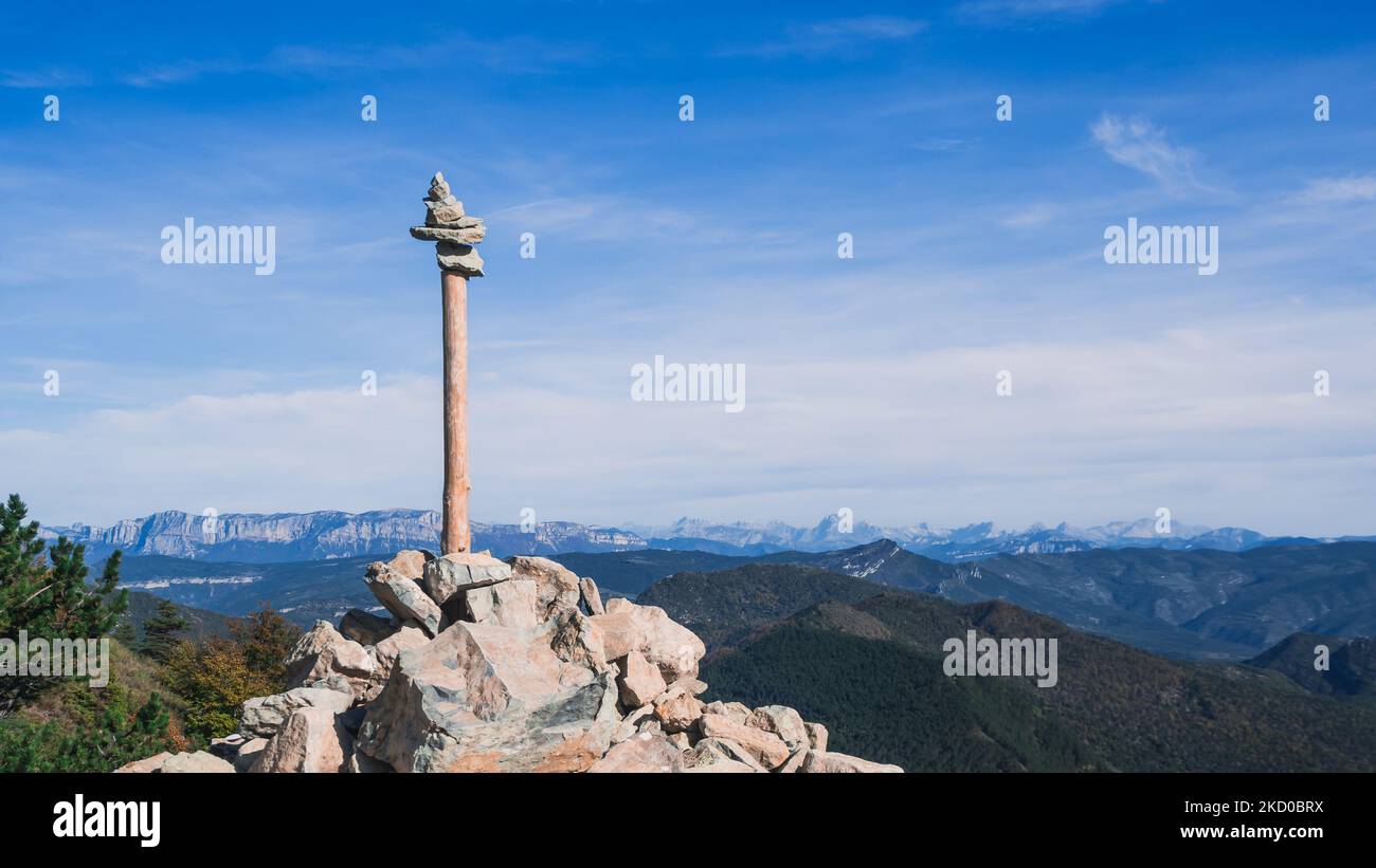 Steinturm mit einem Baumzweig auf einem Berg in den alpen mit Blick auf die umliegenden Berge Stockfoto