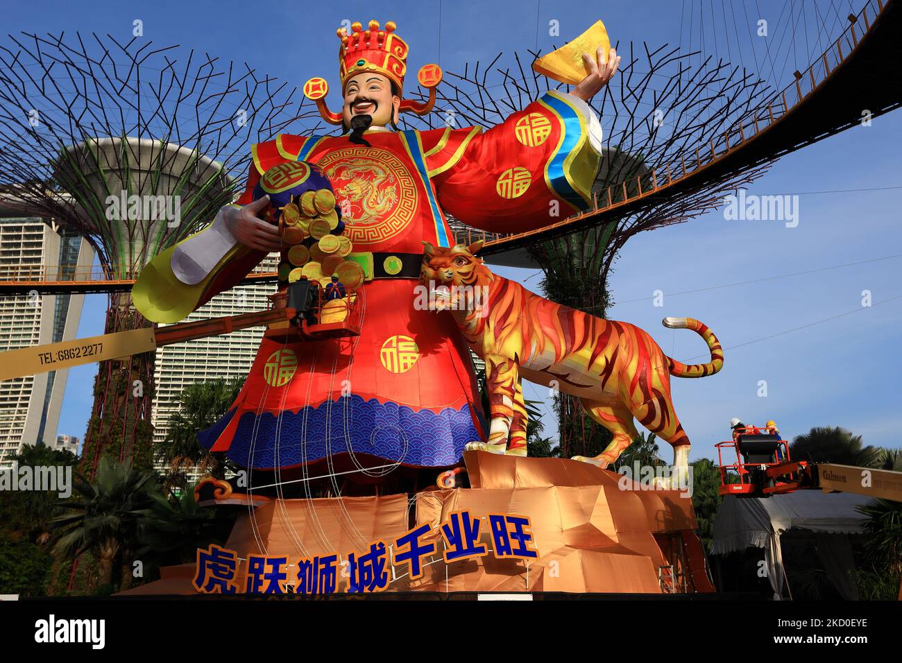 Arbeiter stellten dekorative Goldmünzen auf einer riesigen Laterne auf, auf der der Glücksgott neben einem Tiger zu sehen ist, während Singapur sich inmitten des Anstiegs der Omicron-Variantenfälle während der COVID-19-Pandemie im Supertree Grove auf den Beginn des Jahres des Tigers vorbereitet, Gardens by the Bay am 16. Januar 2022 in Singapur. Am 1. Februar werden Menschen auf der ganzen Welt das Jahr des Tigers begrüßen, einen der am meisten erwarteten Feiertage im chinesischen Kalender. Auch bekannt als das Frühlingsfest oder das Mondneujahr, dauern die Feierlichkeiten etwa 15 Tage. (Foto von Suhaimi Abdullah/NurPhoto) Stockfoto