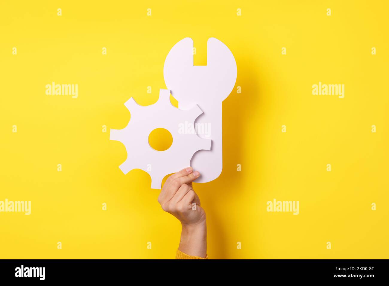 Servicetools-Symbol in der Hand auf gelbem Hintergrund, Reparaturkonzept Stockfoto