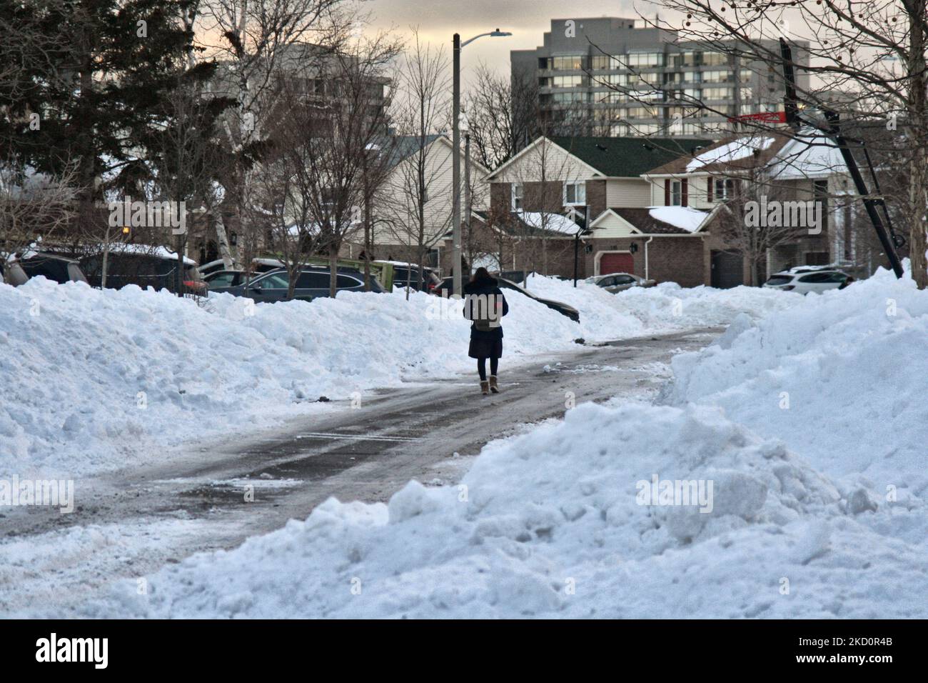 Frau geht am 18. Januar 2022 vor den Häusern in Toronto, Ontario, Kanada, entlang der Straße an schneebedeckten Bergen vorbei. Nach gestern massivem Schneesturm. Der Sturm bedeckte die Stadt mit Schneefällen zwischen 30 und 45 Zentimetern (ein Monat Schnee fiel in nur einem Tag), so Environment Canada. (Foto von Creative Touch Imaging Ltd./NurPhoto) Stockfoto