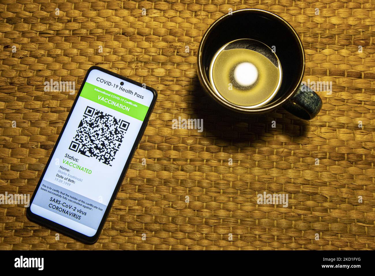 COVID Green Pass-Impfpass neben einer Tasse Kaffee - Foto-Illustration eines Displays eines Mobiltelefons mit einem International COVID Green Pass, einem digitalen Covid-19-Impfpass mit QR, einem internationalen Impfpass oder Gesundheitspass. Foto zum Thema gefälschte QR-Impfzertifikate. Derzeit breitet sich die Pandemie auf der fünften Welle des Coronavirus aus, wobei die omicron-Mutation die dominante Variante ist. Eindhoven, Niederlande am 29. Januar 2022 (Foto: Nicolas Economou/NurPhoto) Stockfoto