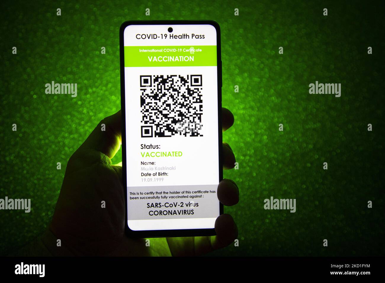 COVID Green Pass-Impfpass - Foto-Illustration einer Hand mit einem Telefon und dem Display des Mobiltelefons mit einem International COVID Green Pass und dunkelgrünem Hintergrund, einem digitalen Covid-19-Symbol-Impfpass mit einem QR, einem internationalen Impfpass oder einem Gesundheitsausweis. Foto zum Thema gefälschte QR-Impfzertifikate. Derzeit breitet sich die Pandemie auf der fünften Welle des Coronavirus aus, wobei die omicron-Mutation die dominante Variante ist. Eindhoven, Niederlande am 29. Januar 2022 (Foto: Nicolas Economou/NurPhoto) Stockfoto