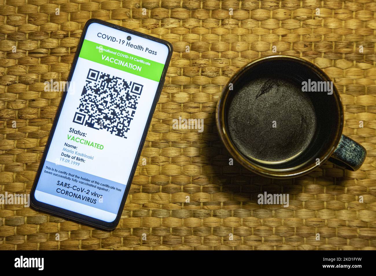 COVID Green Pass-Impfpass neben einer Tasse Kaffee - Foto-Illustration eines Displays eines Mobiltelefons mit einem International COVID Green Pass, einem digitalen Covid-19-Impfpass mit QR, einem internationalen Impfpass oder Gesundheitspass. Foto zum Thema gefälschte QR-Impfzertifikate. Derzeit breitet sich die Pandemie auf der fünften Welle des Coronavirus aus, wobei die omicron-Mutation die dominante Variante ist. Eindhoven, Niederlande am 29. Januar 2022 (Foto: Nicolas Economou/NurPhoto) Stockfoto