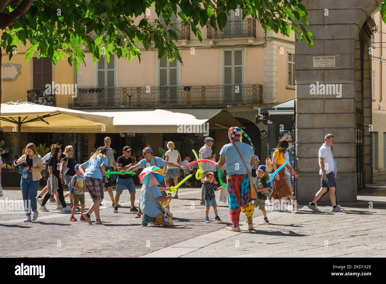 Spielende Kinder, Blick im Sommer der Kinder spielen im Kampf gegen eine Band von Straßenunterhaltern mit Luftballons im historischen Stadtzentrum von Como, Italien Stockfoto