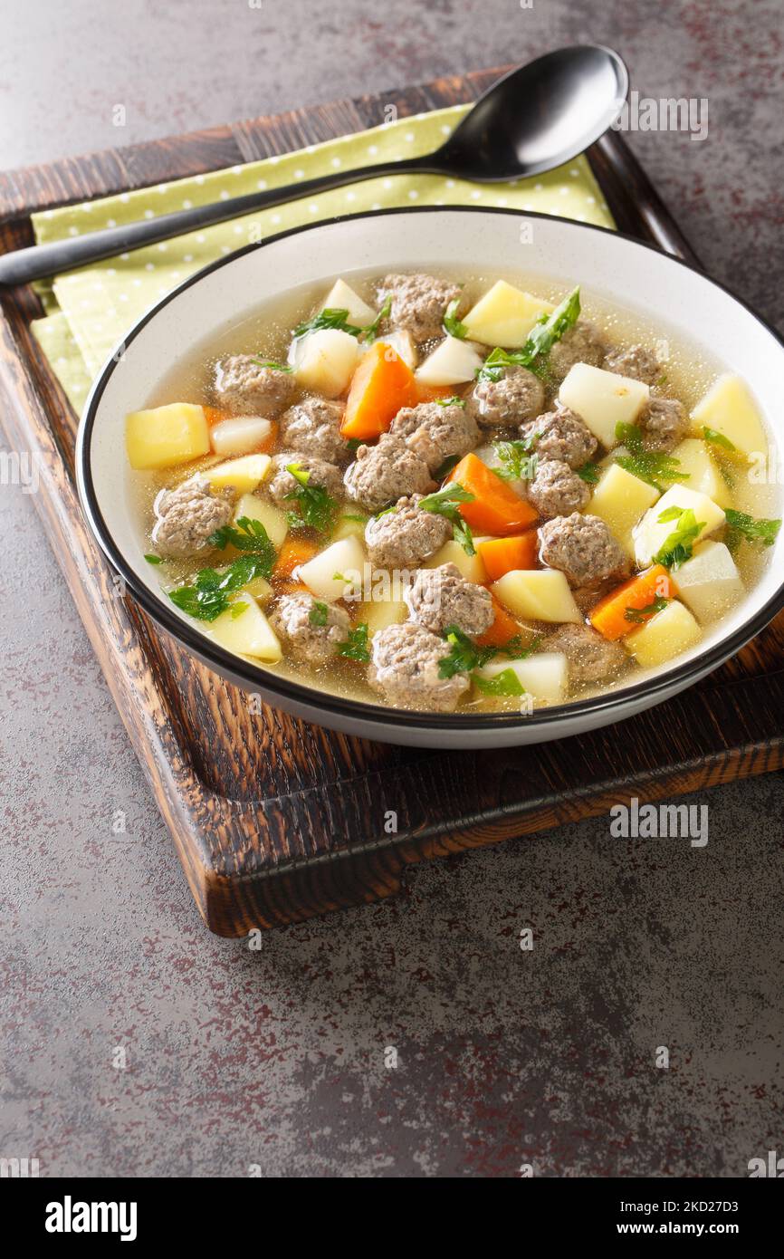 Sodd ist eine traditionelle norwegische Suppe aus gekochtem Hammelfleisch und Fleischbällchen und Kartoffeln, Karotten sind in einer klaren, duftenden Brühe in der Nähe enthalten Stockfoto