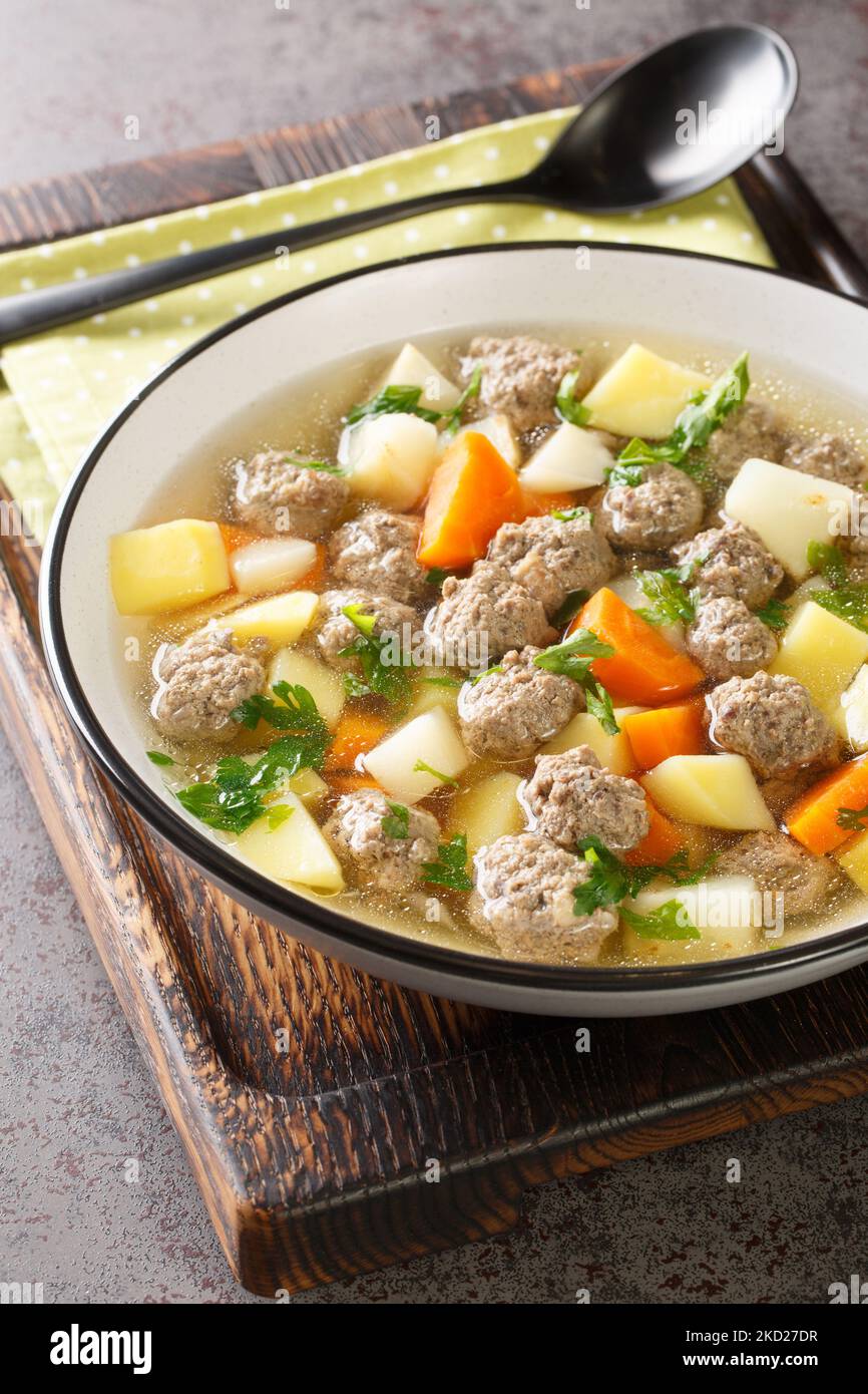 Traditionelle norwegische Suppe Sodd mit Wurzelgemüse und Fleischbällchen aus der Nähe auf einem Teller auf dem Tisch. Vertikal Stockfoto