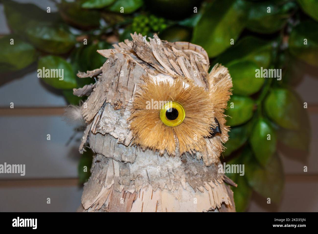 Nahaufnahme des Kopfes einer dekorativen Eule aus Rinde vor einem dunklen, unscharfen Hintergrund Stockfoto