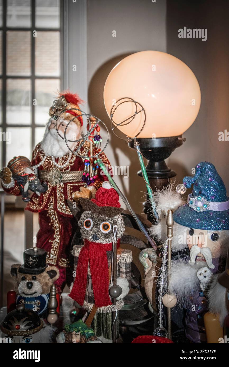 Sammlung von Weihnachtsfiguren wie asiatischer weihnachtsmann und Fischeule sowie Zauberer und Nussknacker auf dem Eingangstisch mit Blick auf die französische Tür Stockfoto