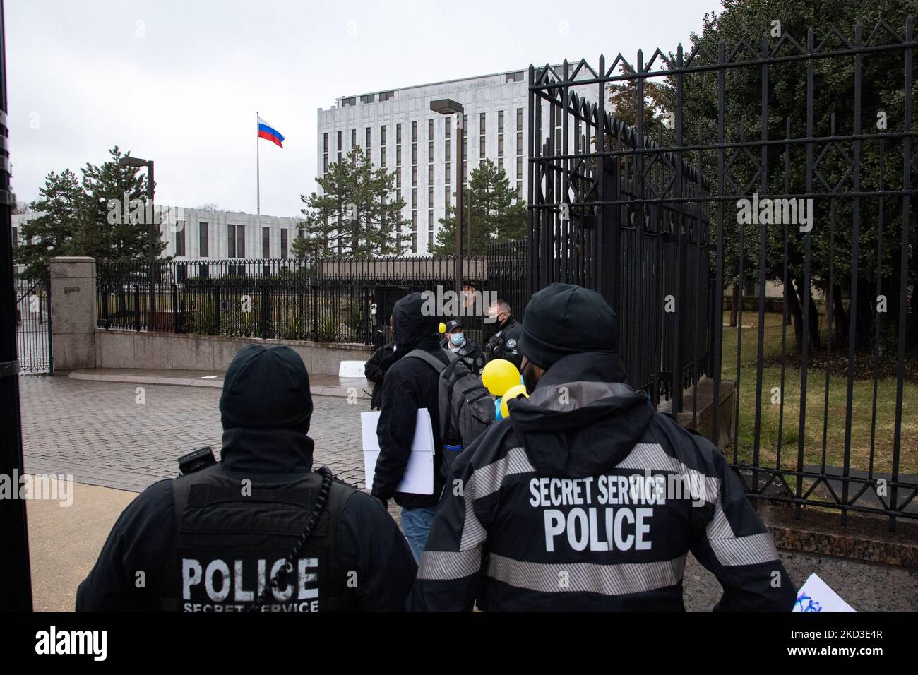 Offiziere des US-Geheimdienstes stehen Wache, als ein Demonstranten, der ein Schild trägt, während eines Protestes vor der russischen Botschaft in Washington, D.C. am 24. Februar 2022 gegen die russische Militärinvasion in die Ukraine vorbeigeht (Foto: Bryan Olin Dozier/NurPhoto) Stockfoto