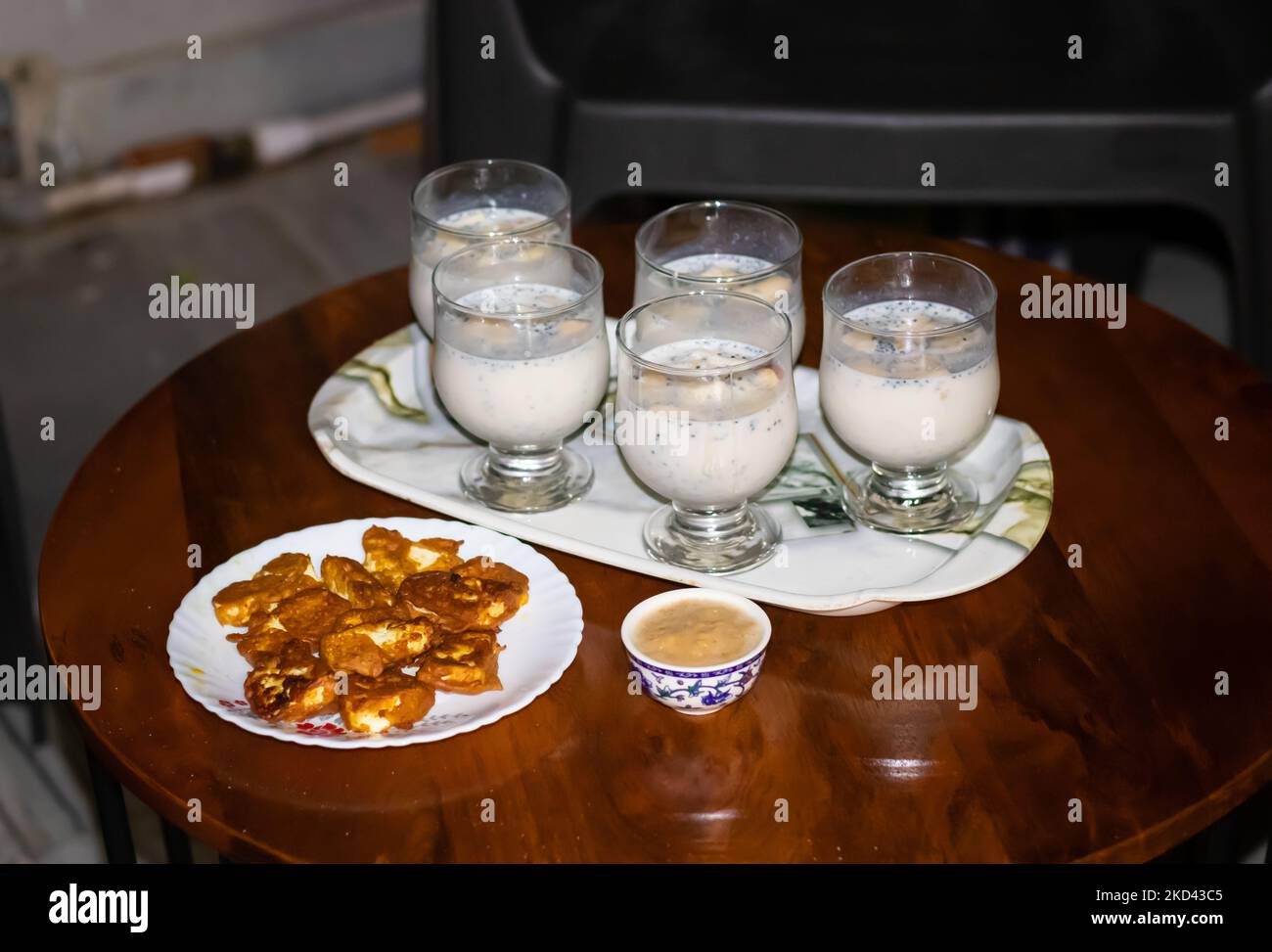 Apfelshake serviert mit indischem Hüttenkäse Pakoda am Couchtisch für die Heimparty Stockfoto